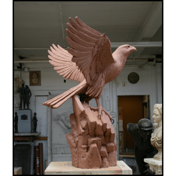photo of clay model of sculpture of eagle with wings open on rocky surface