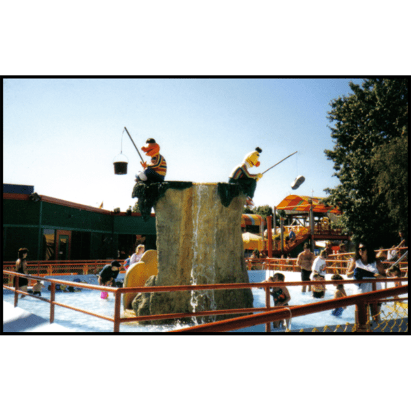 exterior photo of pool with polychromed sculptures of Ernie and Bert fishing at the center