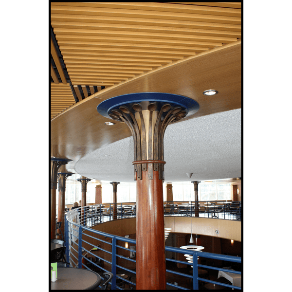 photo of blue and gold capital composed of spoon shapes atop wood support in multi-level cafeteria with woodwork and blue accents