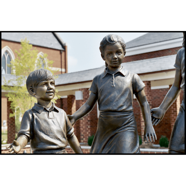 detail photo of bronze sculpture of two children standing in half circle with other children