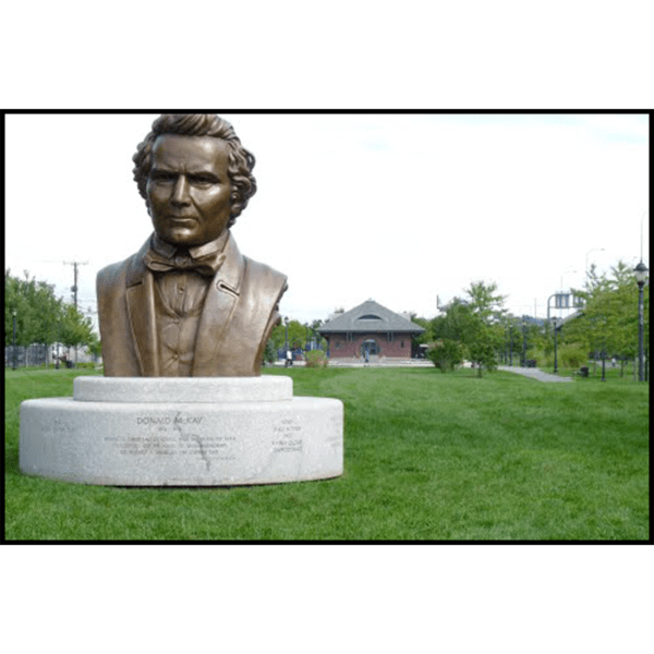 photo of monumental bronze bust of Donald McKay on stone base outdoors on grass