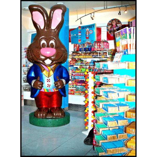 photo of large sculpture meant to look like a chocolate bunny wearing a blue suitcoat and red pants in a candy store
