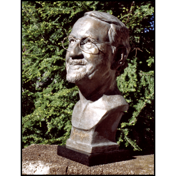 photo of bronze-colored sculpture bust of Gordon Hyatt on stone with trees behind