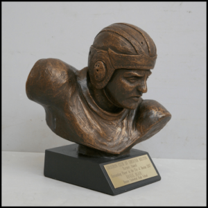 photo of bronze-colored sculpture of bust of a football player with helmet atop a black base with plaque