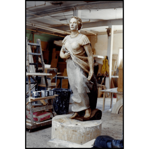 photo of polychromed female figure sculpture leaning forward resembling historic masthead in sculptor's studio