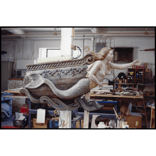 photo of polychromed sculpture of mermaid masthead on ship bow in sculptor's studio