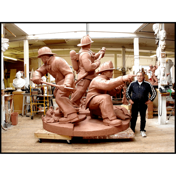 photo of sculptor Robert Shure with clay model of sculpture of three firefighters in action stance