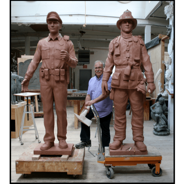 photo of clay models of sculptures of a police officer and a firefighter in studio with sculptor Robert Shure in between
