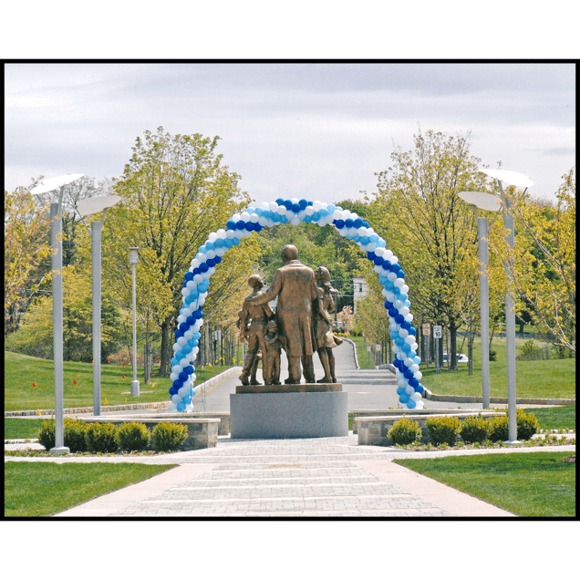 exterior photo of back of bronze sculpture figural group with blue balloon arch