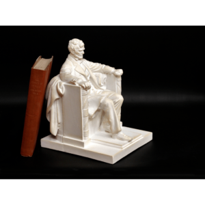 photo of white-colored Lincoln Memorial reduction sculpture with a red book leaning on it