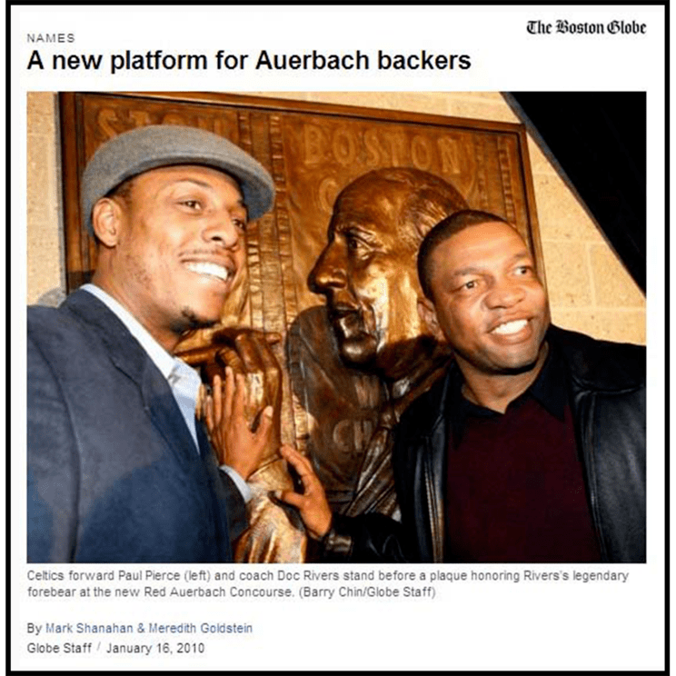 photo of two Celtics players beside bronze relief portrait sculpture of coach Red Auerbach