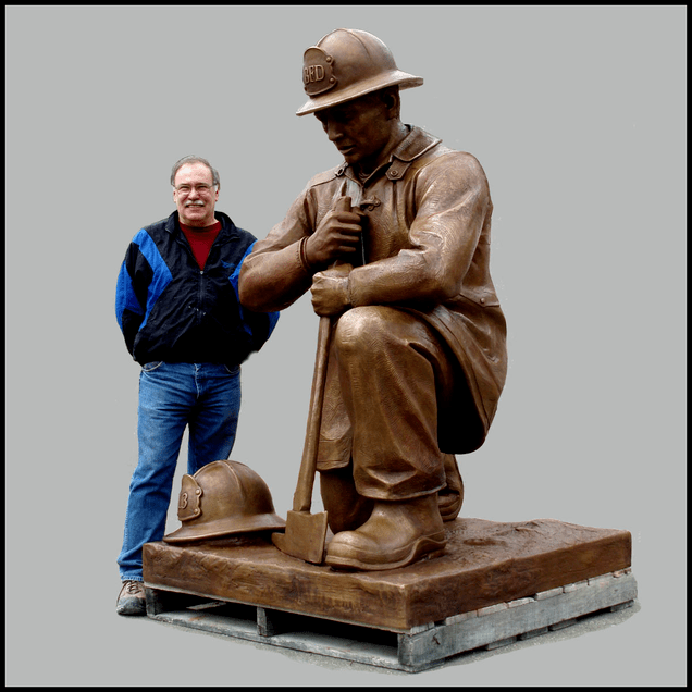 photo of bronze sculpture of kneeling firefighter with sculptor Robert Shure