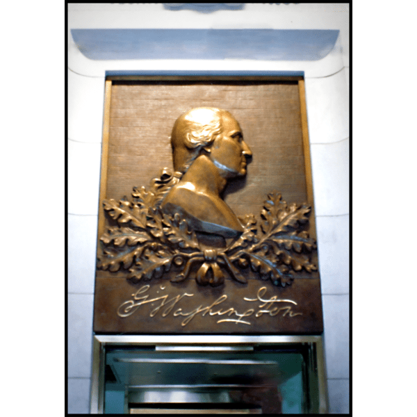 photo of bronze relief portrait of George Washington in profile with oak leaves and his signature above a doorway