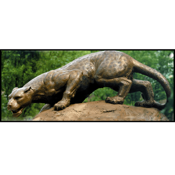 closeup photo of bronze sculpture of leopard stalking on a large rock with greenery behind