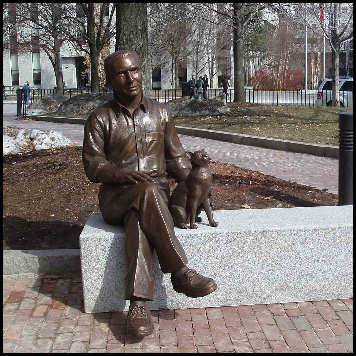 photo of bronze-colored sculpture of seated man crossing his legs petting the cat beside him