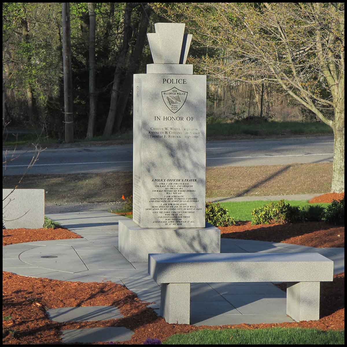 photo of granite memorial surrounded by hardscaping, landscaping, and granite benches