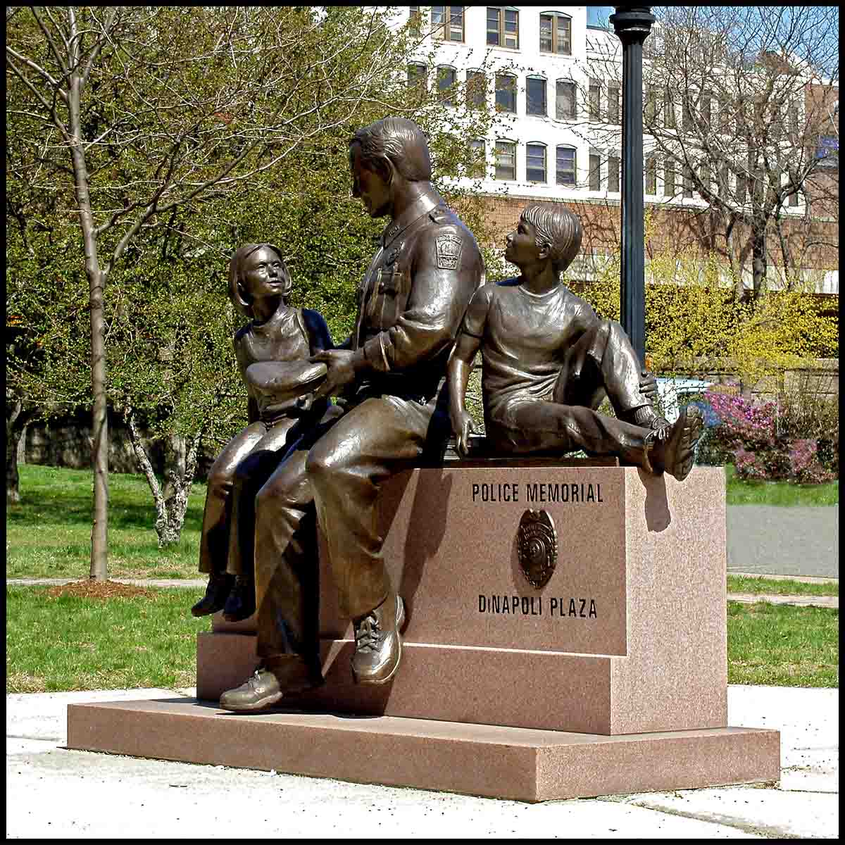 photo of bronze sculpture of adult with two children on stone bench