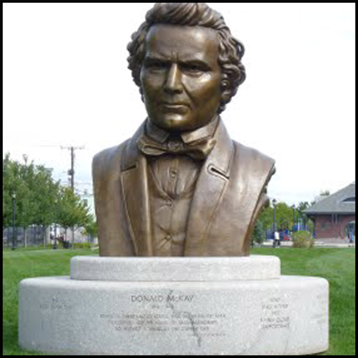 photo of monumental bronze bust of Donald McKay on stone base outdoors on grass