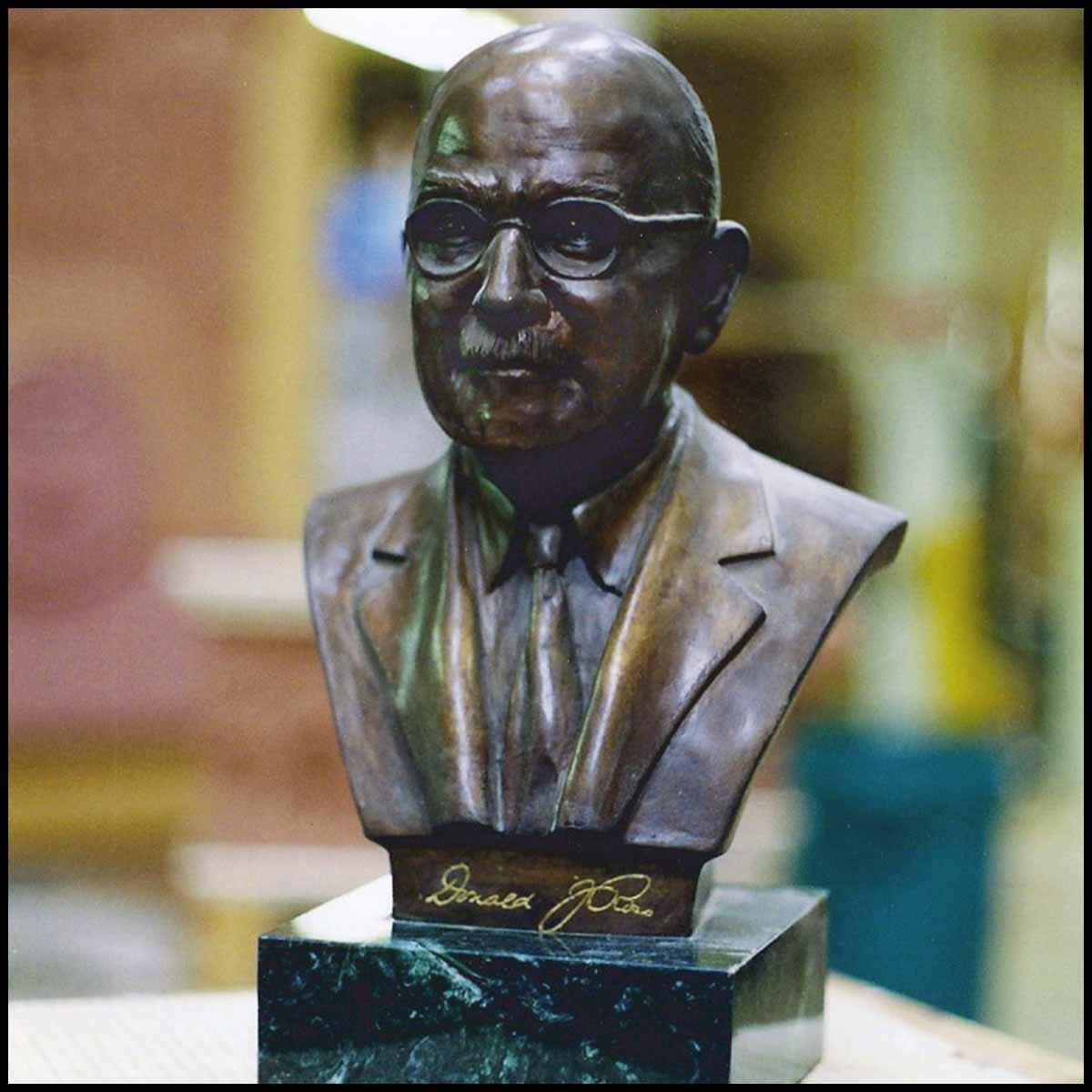 photo of bronze-colored sculpture bust of Donald Ross on black square base on wood work table