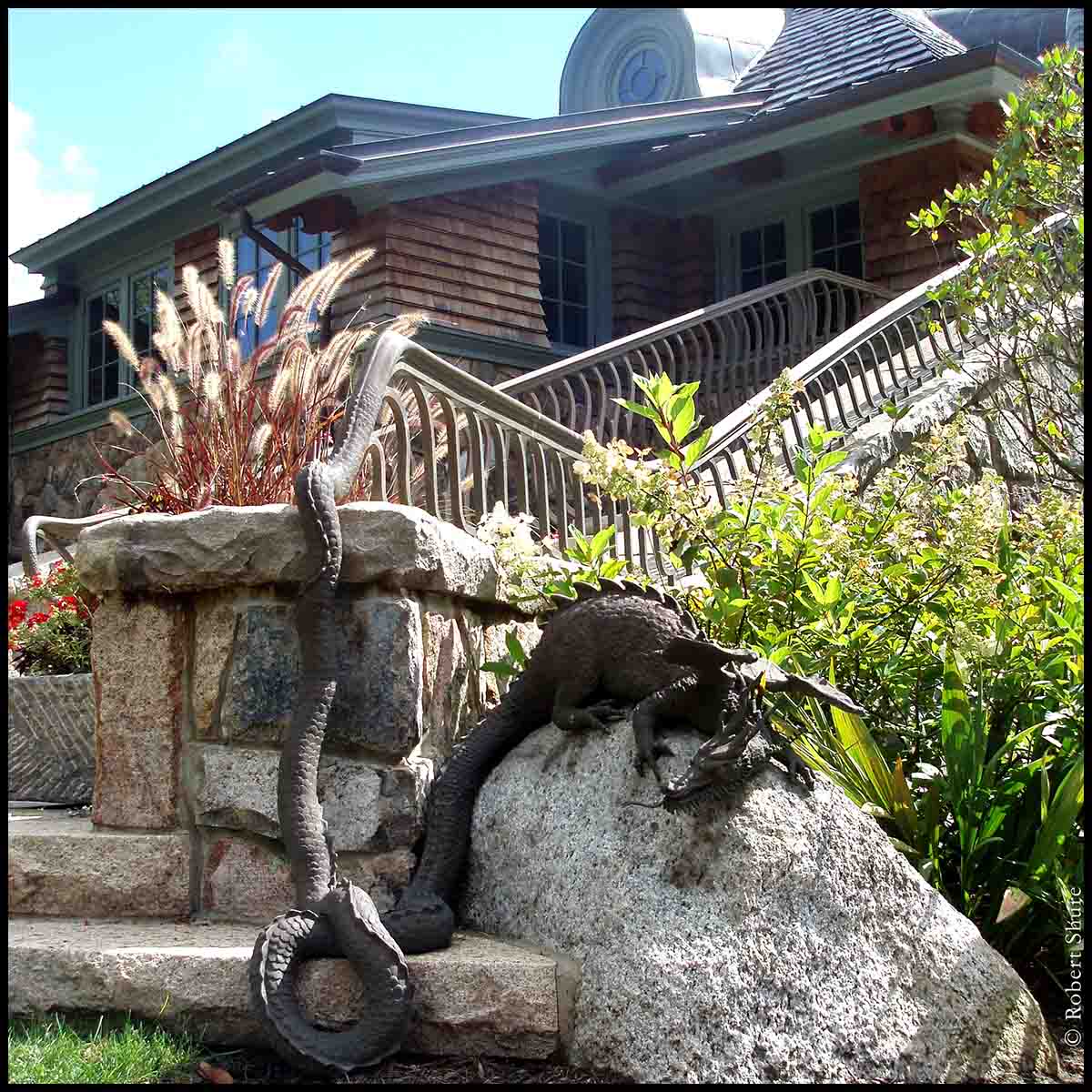 photo of building with stone staircase with a bronze dragon perched on a rock at the bottom