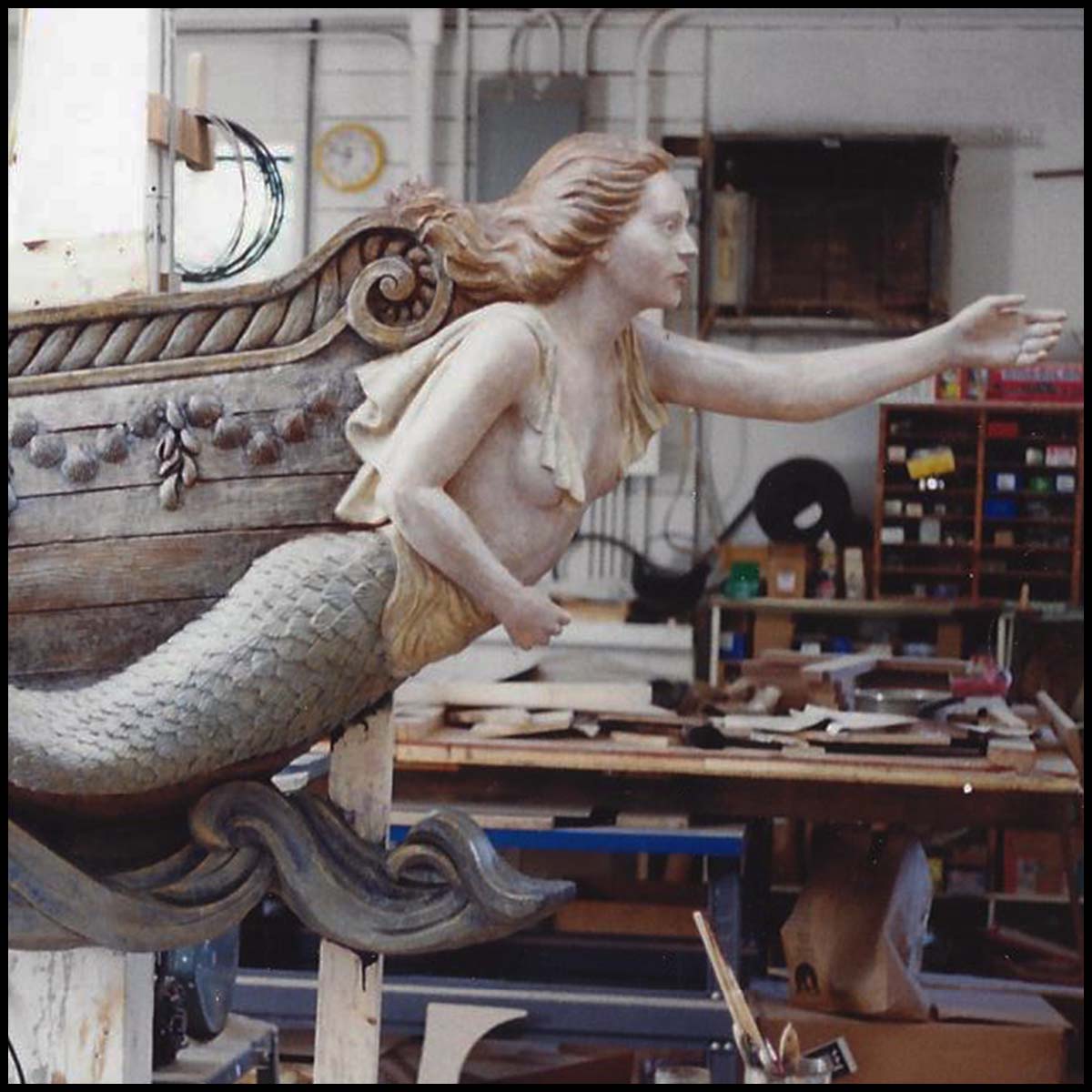 closeup photo of polychromed sculpture of mermaid masthead on ship bow in sculptor's studio