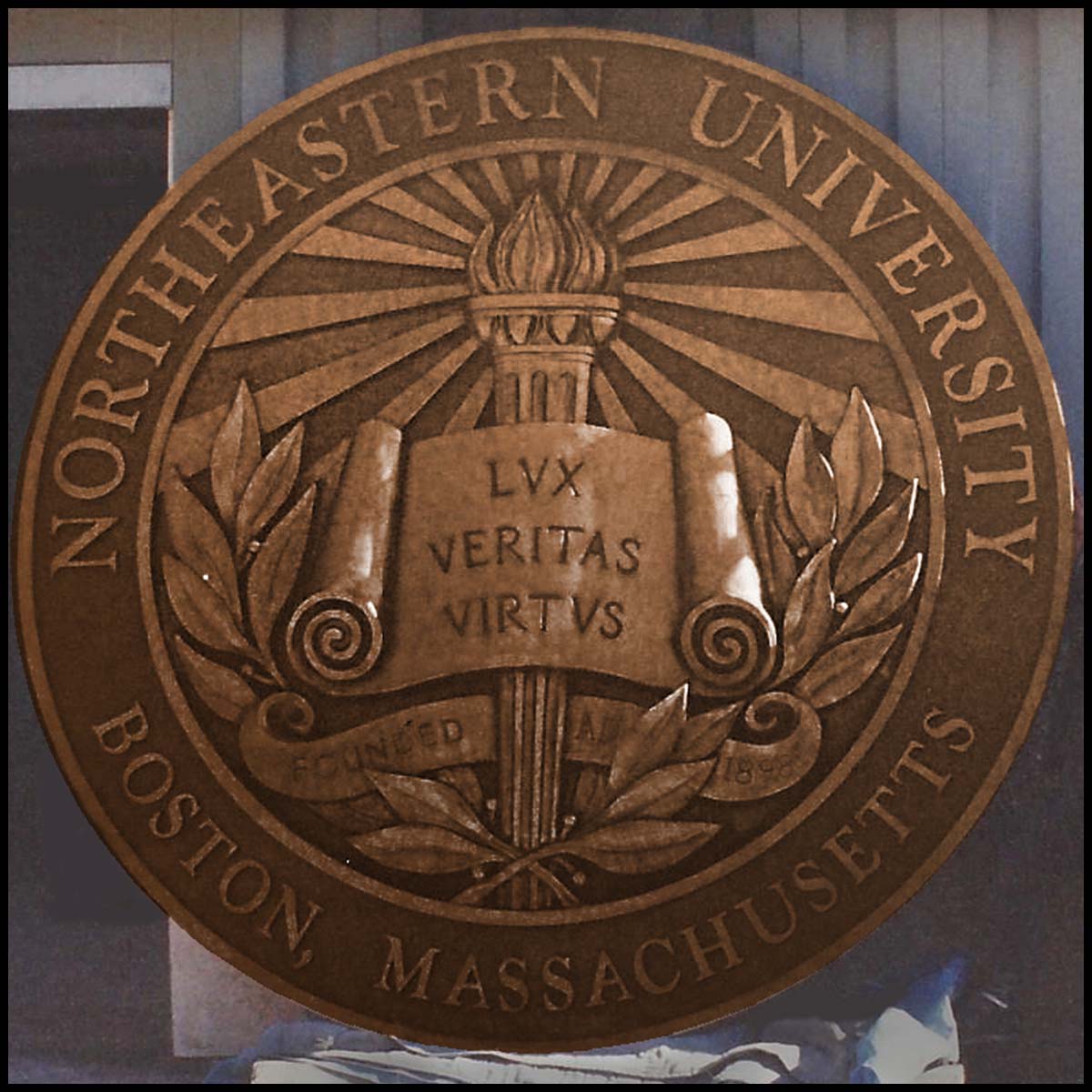 photo of bronze relief sculpture of Northeastern University's seal leaning up against wall