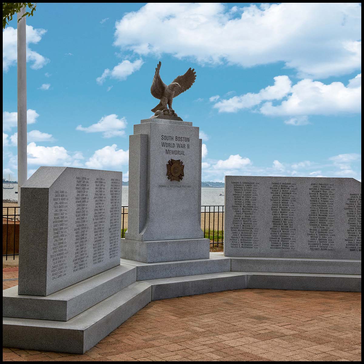 photo of granite monument with bronze eagle sculpture atop central piece in plaza