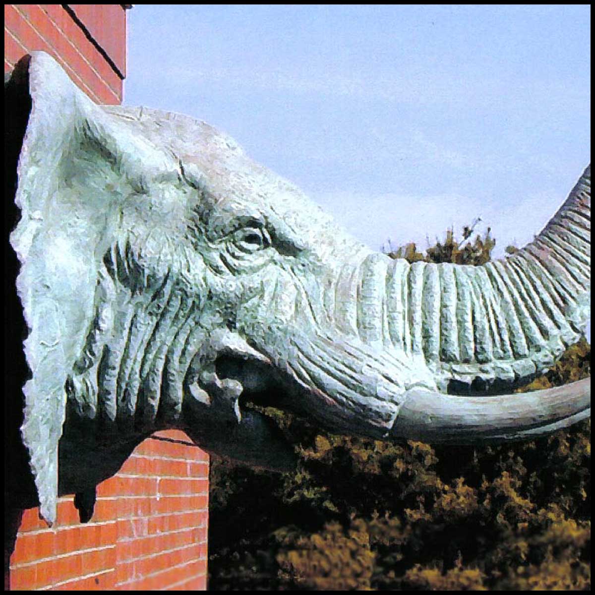 photo of green-colored bronze sculpture of an elephant head on a brick building