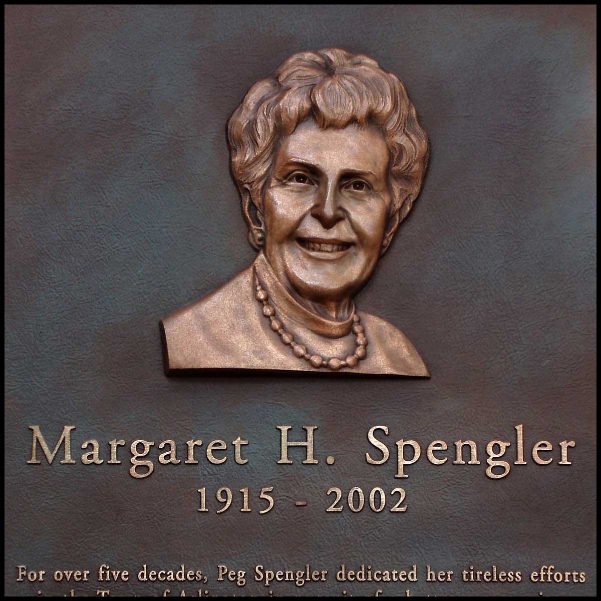 closeup photo of bronze-colored plaque with portrait bust in relief of Margaret Spengler