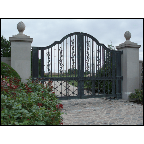 photo of ornamental bronze entrance gate with stone pillars and shrubs to the side